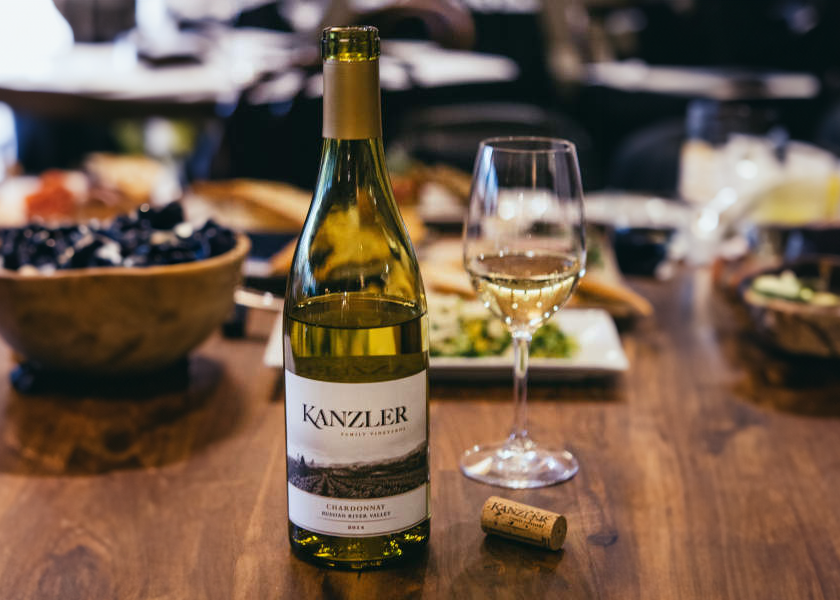 A bottle of Kanzler Chardonnay on a table with food.
